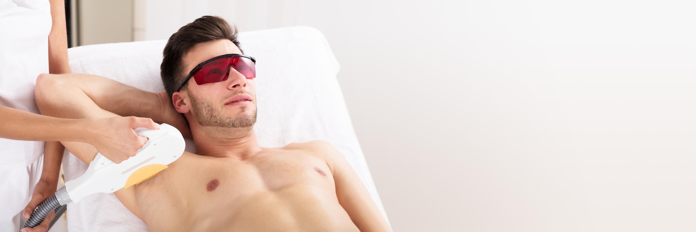 A man with sunglasses sitting on top of a bed.